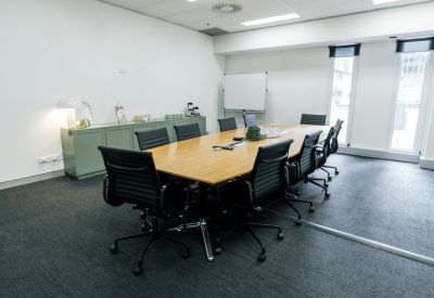 Professional boardroom with a large timber table, black chairs, and a white whiteboard.