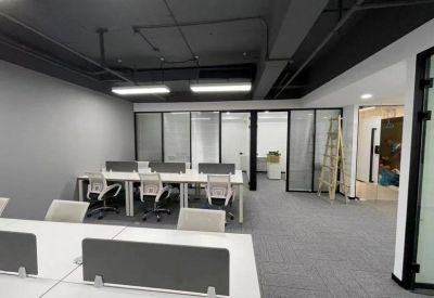 Modern open-plan office with grey walls and white workstations.