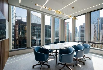 Conference room with a white marble table and blue velvet chairs surrounded by glass walls.