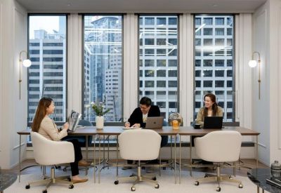 Coworking space with a long wooden table, white swivel chairs, and large windows.