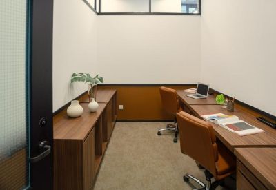 Private two-person internal office suite with wooden desks and leather chairs.
