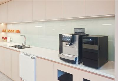 Sleek office kitchenette with professional coffee machine and minimalist cabinetry.