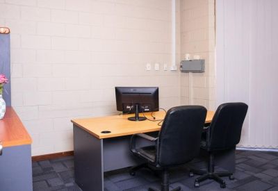 Two-person private office with a wooden desk and black swivel chairs.