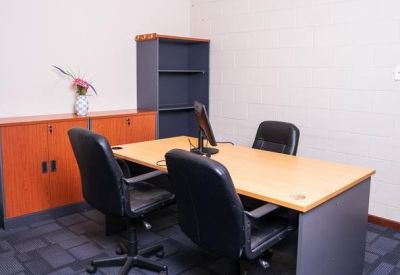 Small office suite featuring a wooden desk, two chairs, and a storage cupboard with flowers.