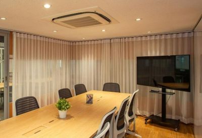 Bright conference room with a large wooden table and wall-mounted monitor.