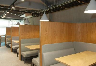 Wooden semi-private booths with grey cushioned seating and pendant lighting.
