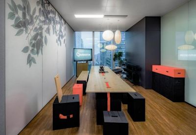 Long wooden collaboration table featuring black cube stools and a botanical wall mural.