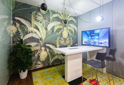 Small meeting room with a tropical leaf feature wall, white table, and integrated wall monitor.