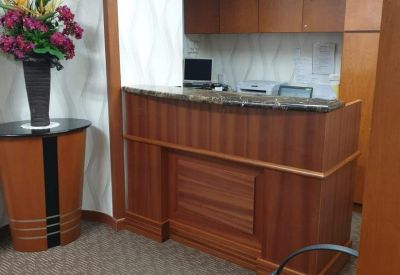 Wooden reception desk at International Plaza with marble countertop and floral arrangement.