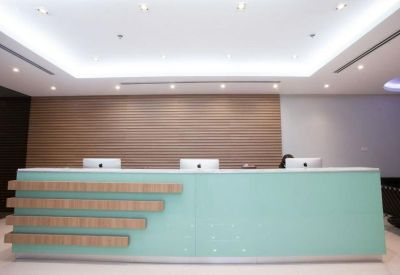 Modern reception desk in pale green with light wood accents and warm lighting.