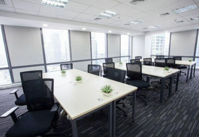 Bright open-plan office with white desks, mesh chairs, and potted plants.