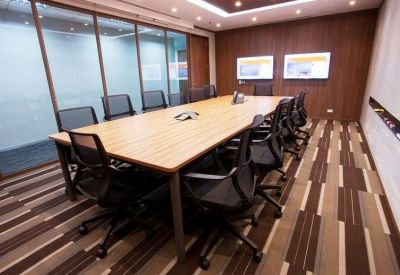 Professional boardroom with a large wood table, black chairs, and dual presentation screens.