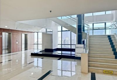 Bright building lobby featuring a grand staircase and polished stone floors.