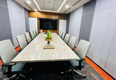 Long formal meeting room with a marble table, grey ergonomic chairs, and a large wall-mounted screen.