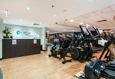 Fitness center reception desk with Surge Fitness branding and cardio equipment.