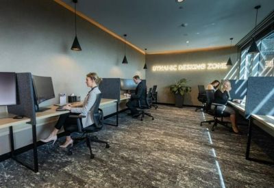 Coworking zone with partitioned desks, pendant lighting, and warm wood flooring.