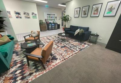 Spacious communal lounge area with patterned rugs, varied seating, and wall art.