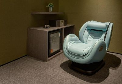 Private relaxation room featuring a modern light blue massage chair and a small refreshment fridge.