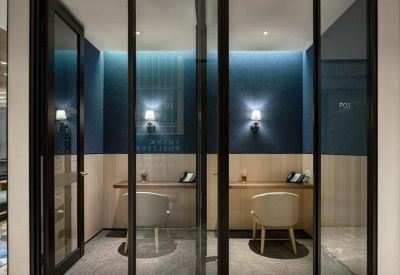 Symmetrical workstations behind glass partitions with dark blue feature walls and individual wall lamps.