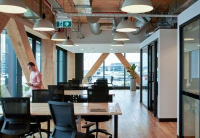 Open-plan office space featuring timber structural beams and rows of modern desks.