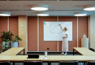 Professional meeting room with a U-shaped table and a person writing on a whiteboard.