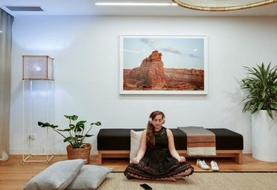 Tranquil wellness room with a person meditating on a mat in front of a framed landscape photo.