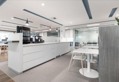 Bright breakout kitchen and dining area with sleek white cabinetry and bar seating.