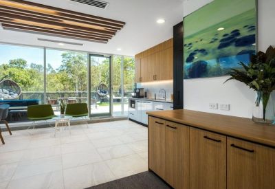 Breakout space with wooden cabinetry, a wall-mounted landscape photo, and views of greenery.