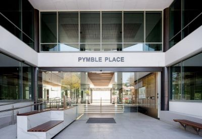 Building entrance with Pymble Place signage above glass doors and outdoor seating.
