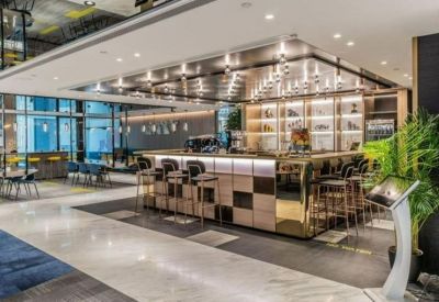 Modern communal cafe and bar area with warm lighting and wooden accents.