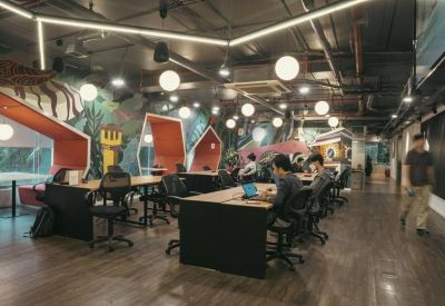 Vibrant communal coworking area with hexagonal ceiling lights and diverse seating options.