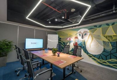 Meeting room featuring a wooden table, ergonomic chairs, and a colorful owl mural.