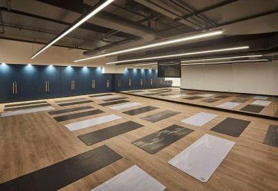 Spacious yoga studio with multiple mats laid out on a light wood floor.