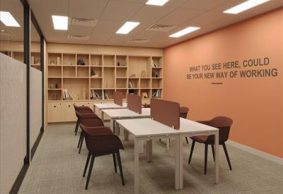 Co-working space with shared white desks, maroon chairs, and wall-to-wall shelving.