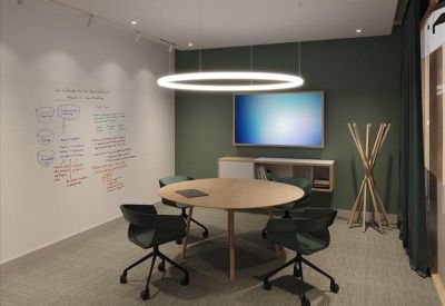 Meeting room with a round table, teal chairs, and a halo pendant light.