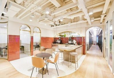 Bright office kitchen and breakout zone with wooden floors and exposed ceiling pipes.