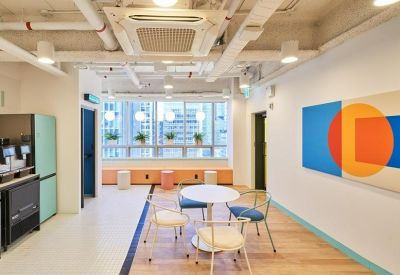 Bright coworking area with a round table, colorful wall art, and large windows.