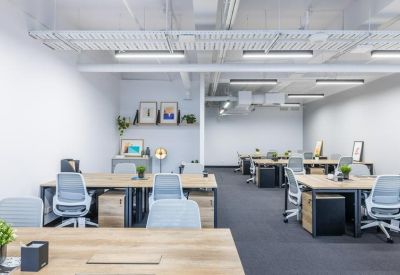 Bright open-plan office with timber desks and ergonomic blue chairs.