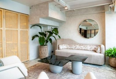 Bright breakout area featuring a curved sofa, round mirror, and indoor plants.