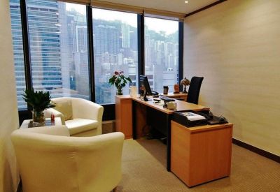 Bright private corner office with light wood furniture and expansive city views.
