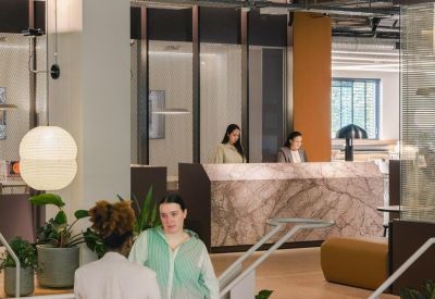 A warm reception area with a marble front desk and wooden staircase.