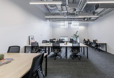 Modern open-plan workspace with multiple rows of desks and industrial-style ceiling.