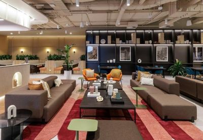 Spacious communal lounge with plush sofas, colorful armchairs, and decorative shelving.