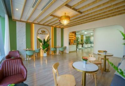Chic lounge area featuring wood-slat ceilings, a gold chandelier, and stylish green and red armchairs.