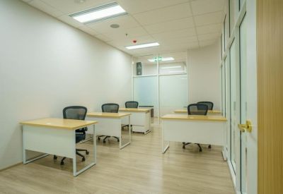 Private office space with four individual wooden desks and ergonomic black chairs.