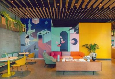 Vibrant communal lounge with a space-themed mural, colorful sofas, and warm wood-slatted ceiling.