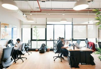 Bright open-plan office with wooden desks and large windows.