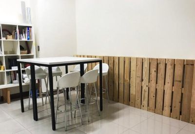 Breakout area with a high table, white stools, and a decorative wood pallet wall.