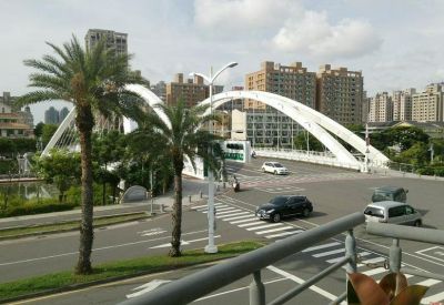Outdoor balcony view overlooking a white arched bridge and city skyline.
