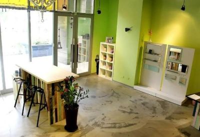 Bright reception or lounge area with a light wood bar counter, stools, and vibrant green feature walls.